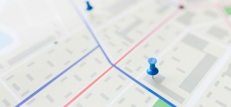 cartography, location and navigation concept - close up of map or city plan with pin