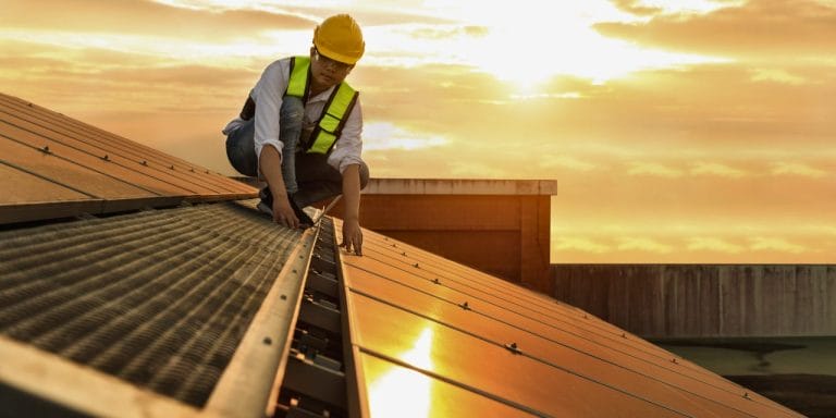 Solar installer on a rooftop inspecting solar panel placement